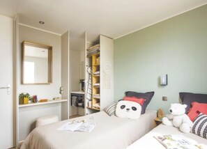 A bedroom with a bed, a desk, a wardrobe, and a mirror.