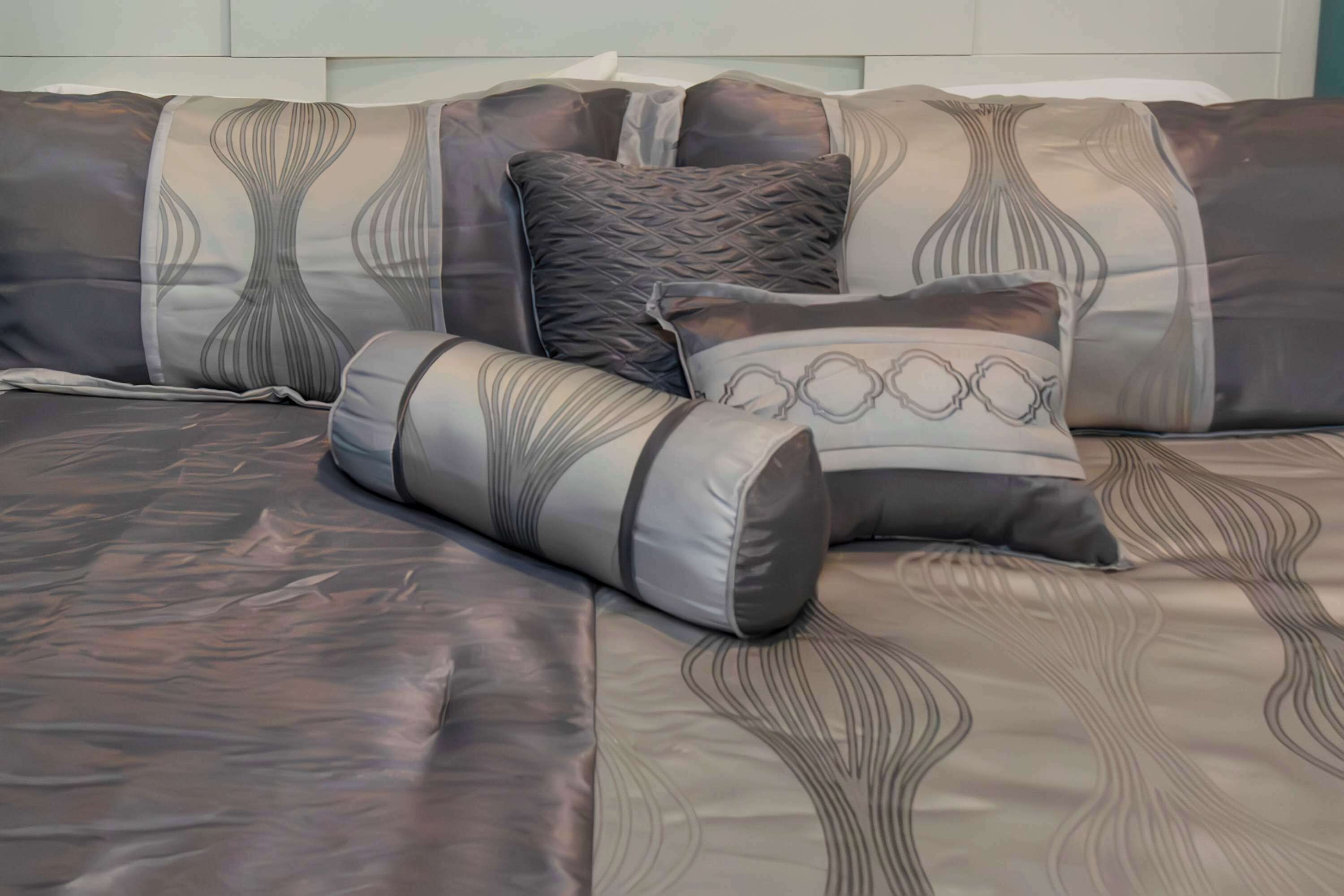 A bed with a patterned bedspread and multiple pillows.