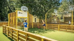 Un terrain de basket-ball avec une clôture jaune, un panier de basket et une zone de jeu délimitée par un filet.