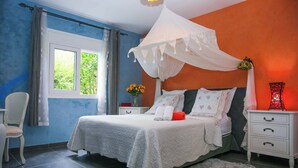A bedroom with a bed, a nightstand, a chair, a window, and a curtain.
