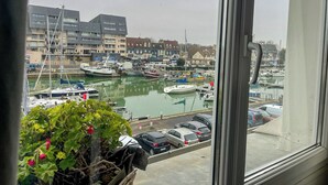 Ein Yachthafen mit vertäuten Booten, ein Parkplatz mit Autos und Gebäude im Hintergrund.