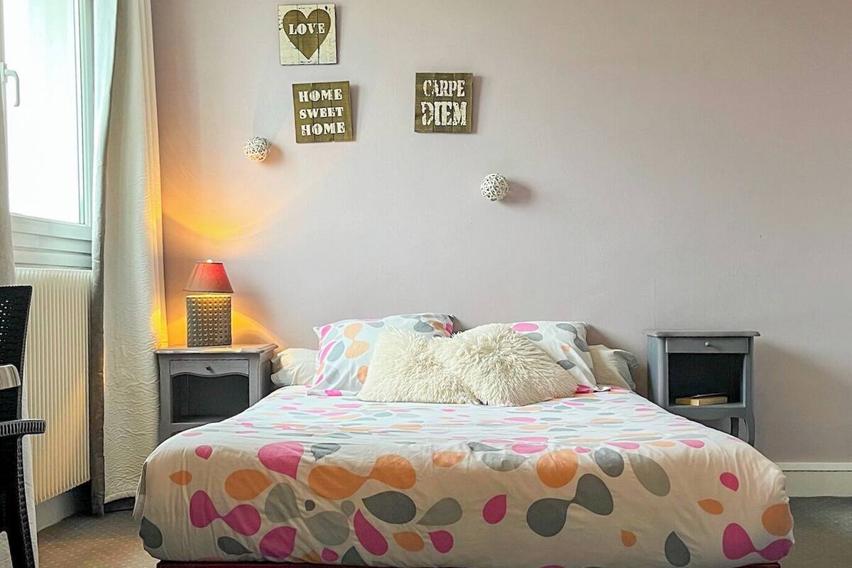 A bedroom with a bed, two bedside tables, a lamp, and wall decorations.