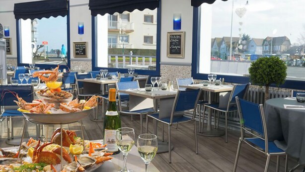 Ein Fischrestaurant mit Tischen und Stühlen, einer großen Platte mit Meeresfrüchten und Weingläsern.
