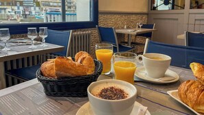 Ein Frühstückstisch mit Croissants, Orangensaft und Kaffee, dazu eine Speisekarte.