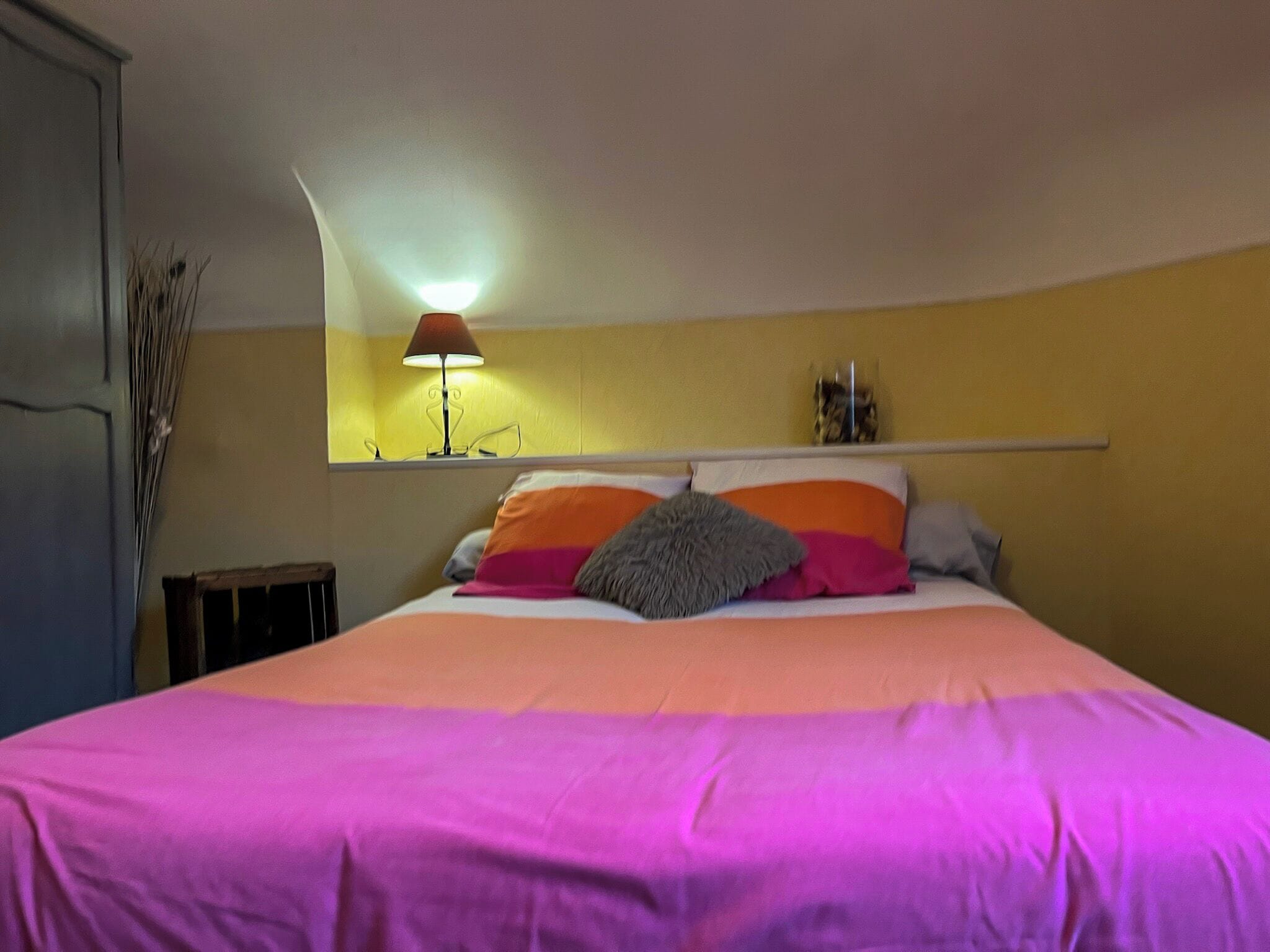 Une chambre à coucher avec un lit, une table de chevet, une lampe et un miroir au mur.