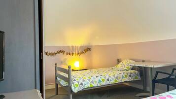 Una cama individual con un edredón estampado con motivos geométricos, una mesita de noche y una lámpara de pared.