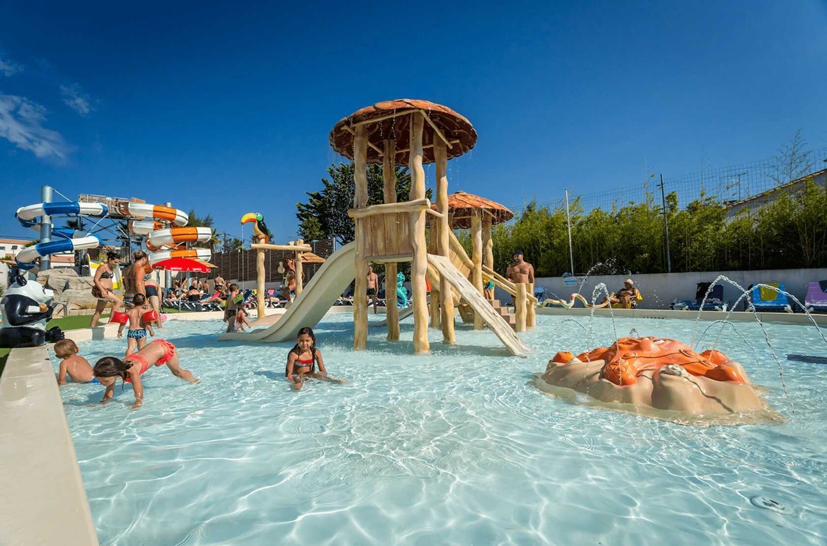 Ein Wasserpark mit Rutschen, einer Holzspielanlage und einem Schwimmbecken.