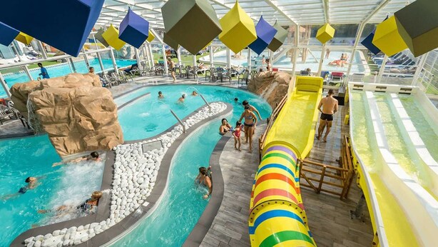 A pool area with a slide, multiple swimming pools, and a rocky feature.