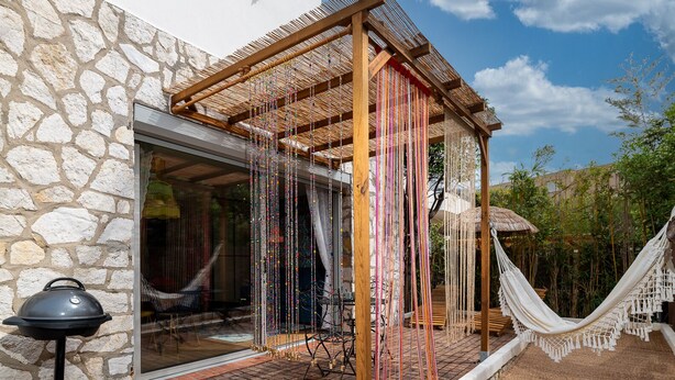 Un bâtiment en pierre doté d’une pergola en bois, d’un hamac et d’un barbecue à l’extérieur.