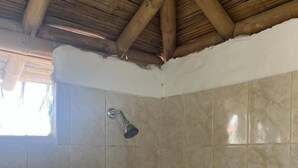 Zona de ducha con barra de apoyo metálica, cabezal de ducha y pared de azulejos con un borde decorativo.