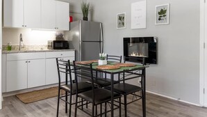 Une cuisine moderne avec des meubles blancs, un réfrigérateur en acier inoxydable, un four à micro-ondes et un coin repas comprenant une table et des chaises.