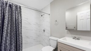 Une salle de bain avec douche, toilettes et lavabo.