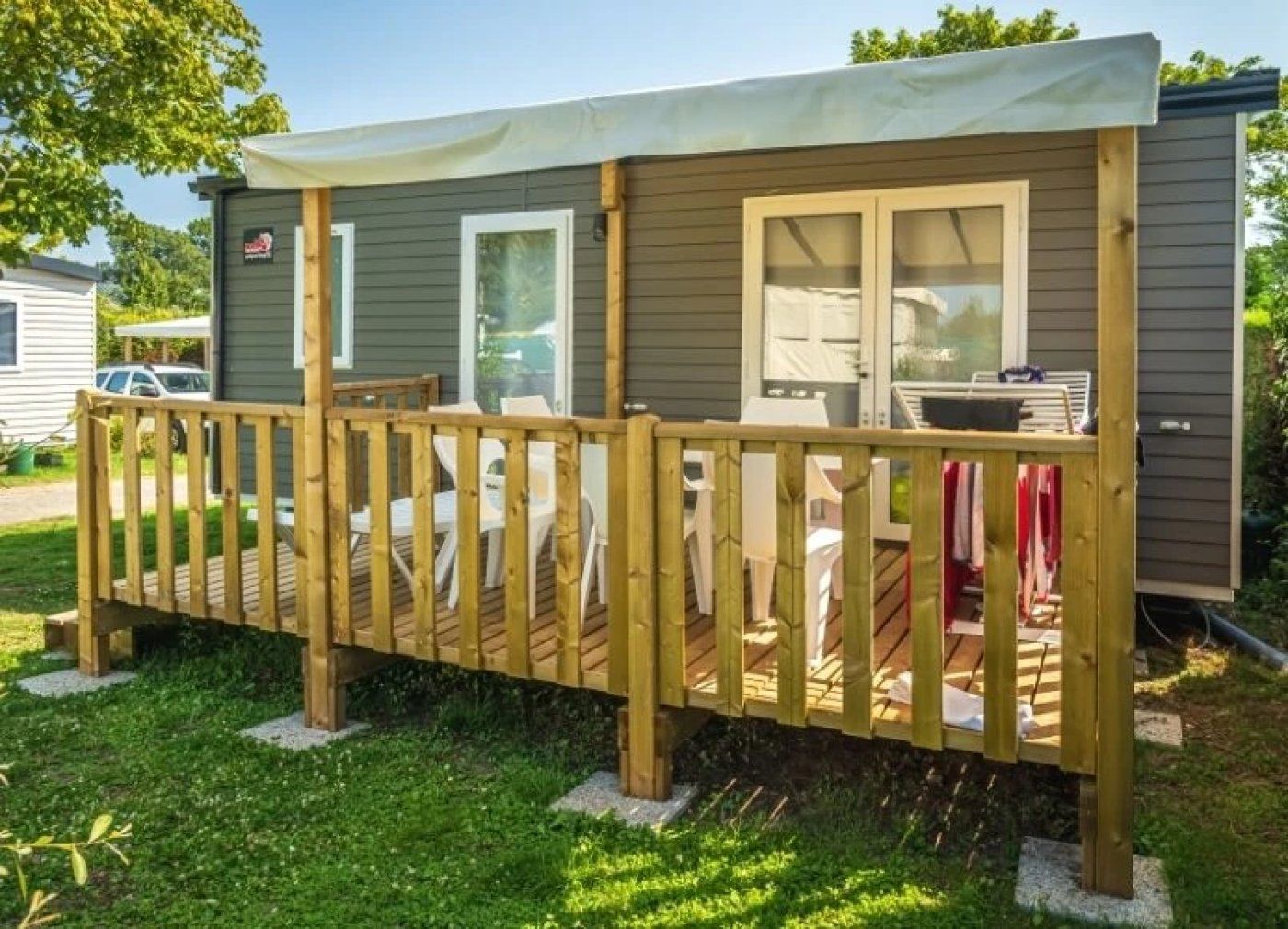 Een stacaravan met een houten terras, een overdekte veranda en een klein zitgedeelte buiten.