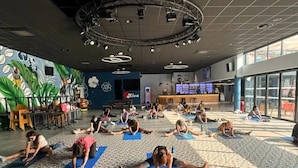 A spacious indoor area with a high ceiling, multiple yoga mats laid out on the floor, and a stage with lighting equipment. - ZEcamping animations espace aquatique piscine couverte et restaurant (Saint-Hilaire-de-Riez)