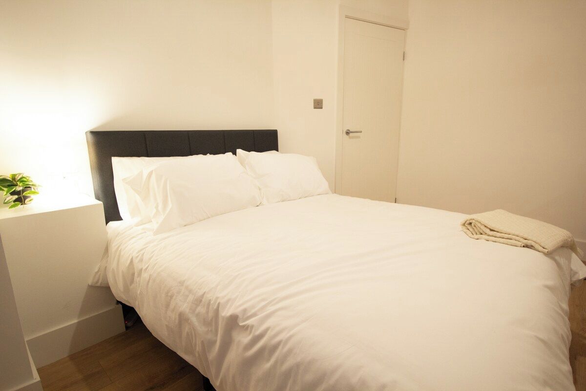 Un lit bien fait, avec du linge de lit blanc, dans une pièce au design simple et épuré.