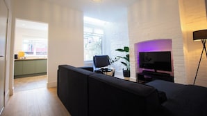 A modern living room with a black sofa, a flat-screen TV, and a potted plant.