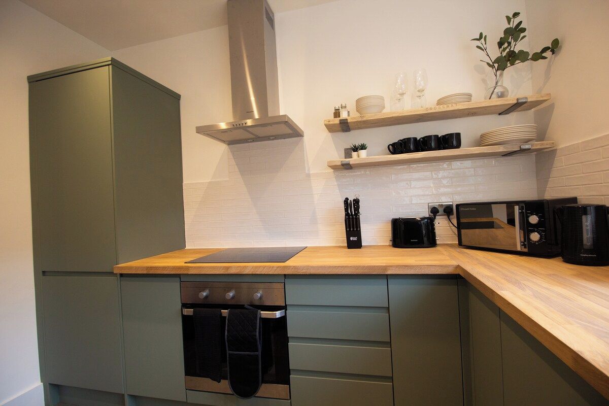 A compact kitchen with a built-in oven, a microwave, and a stainless steel range hood.
