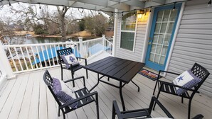 A covered porch with a table and chairs, a view of a lake, and a blue door.
