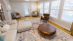 A spacious living room with a large, patterned rug, a round coffee table, and two sofas with cushions.