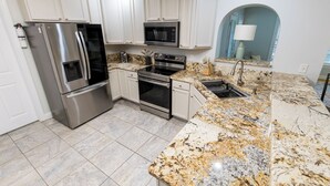 A modern kitchen with stainless steel appliances, granite countertops, and white cabinetry.