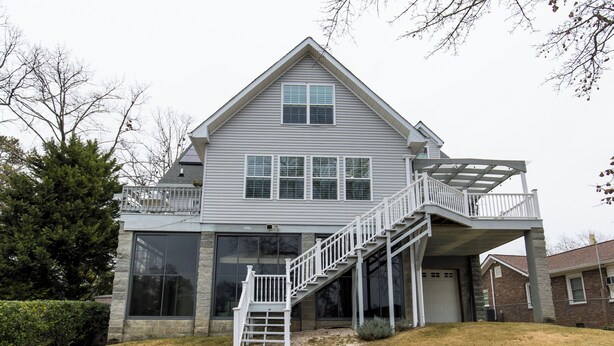 A two-story house with a covered porch and a staircase leading to a balcony.
