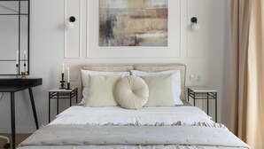 Une chambre à coucher comprenant un lit, des tables de chevet, un bureau et un tableau abstrait accroché au mur.