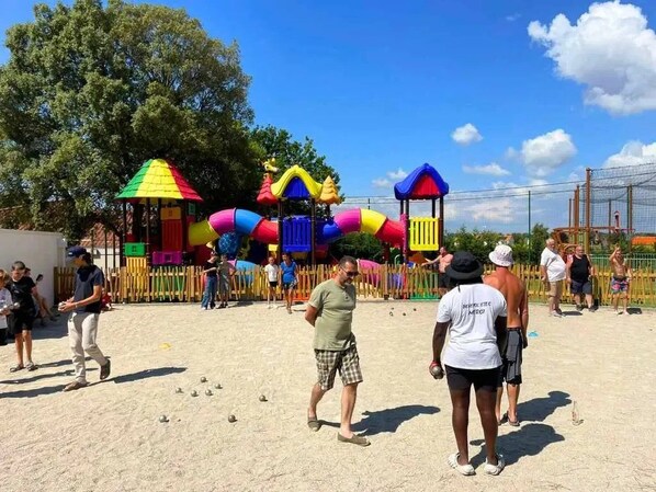 Une aire de jeux avec des structures colorées et un sol sablonneux.