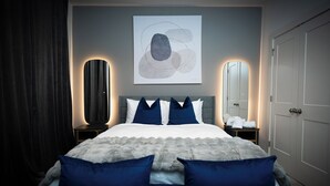 Un dormitorio moderno con una cama grande, dos mesitas de noche, un espejo y un cuadro en la pared.