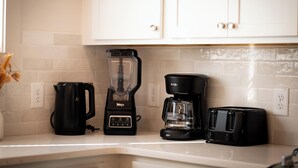Una cocina con armarios blancos, una cafetera, una licuadora y un tostador sobre la encimera.