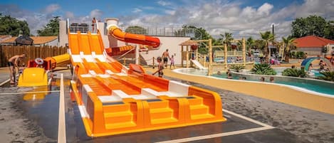 Parque acuático con un tobogán de agua grande, piscina y diversas estructuras recreativas.