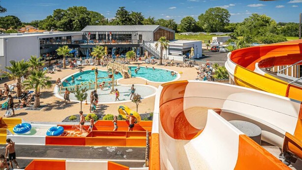 A water park with multiple pools, slides, and a covered area with seating.