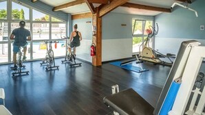 Une salle de sport équipée de vélos d’exercice, d’un vélo stationnaire et d’un banc de musculation.