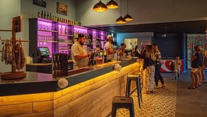 Un espace bar comprenant un comptoir, des tabourets de bar et une variété de bouteilles et de verres.