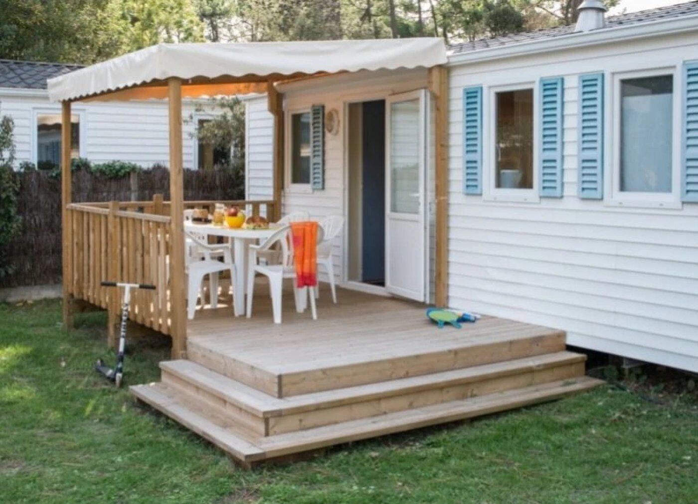 Un espace extérieur abrité, avec une table et des chaises, une terrasse en bois et une petite marche menant à une porte.