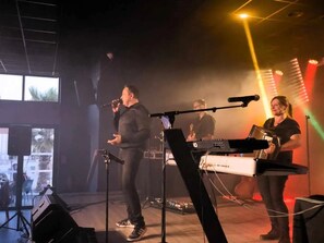 A band performing on a stage with a keyboard and microphone stand.