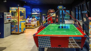 Una mesa de billar con máquinas recreativas a su alrededor, incluyendo 'Double Pong' y 'Mystery Tower'.