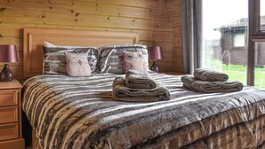 Un dormitorio con paneles de madera, una cama, almohadas y toallas.