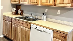 A kitchen with wooden cabinets, a dishwasher, a sink, and a countertop. - Your Little Guest House (Kennewick)