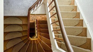 A spiral staircase with wooden handrails and carpeted steps.
