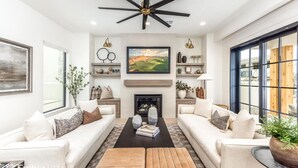 A modern living room with two sofas, a coffee table, a fireplace, and a large window.
