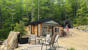 Een chalet met terras, omringd door een bos.