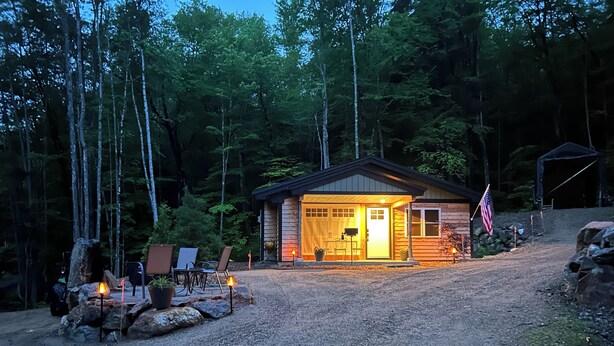Een chalet met een veranda, buitenmeubels en een vlag.