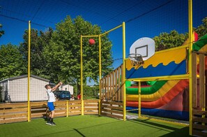 Een basketbalveld met een net, een basketbalring en een houten omheining.