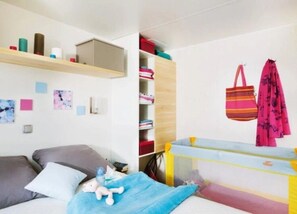 Ein Kinderzimmer mit einem Etagenbett, einem Schreibtisch und Regalen mit verschiedenen Gegenständen.