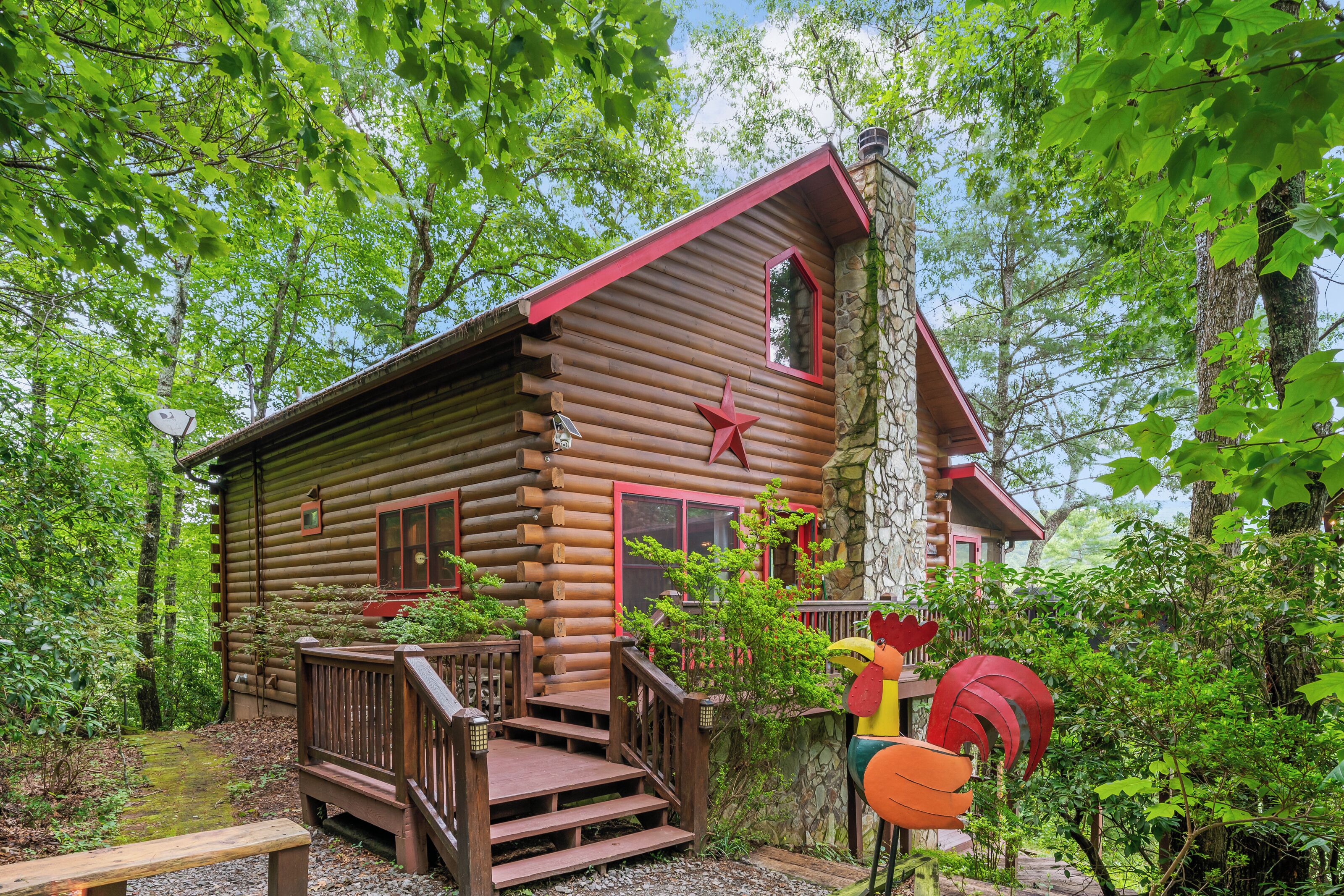 Une cabane en rondins avec une terrasse en bois, une décoration en forme d’étoile rouge et une cheminée en pierre.