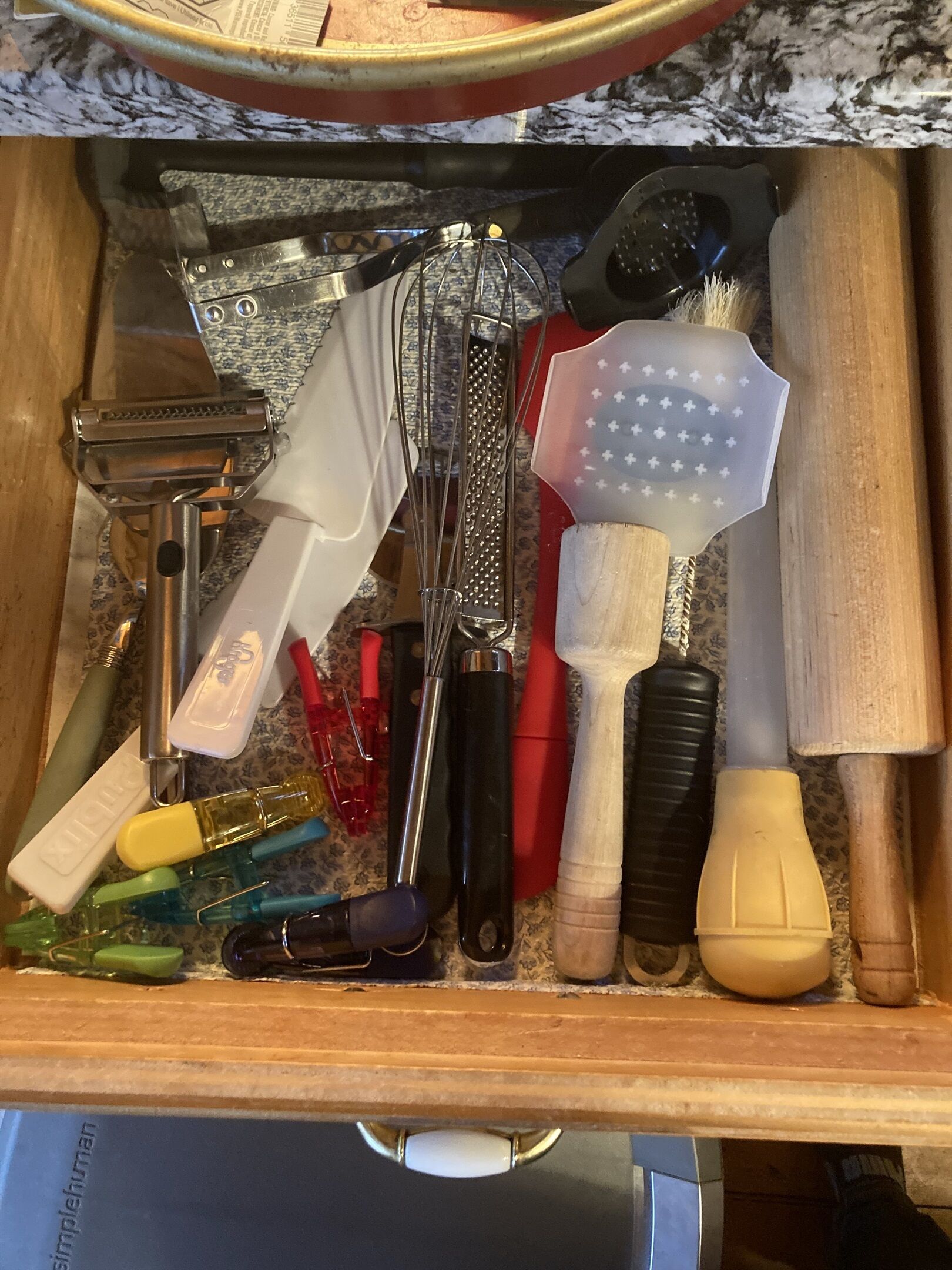 A drawer containing various kitchen utensils and tools, including a grater, whisk, and spatula.