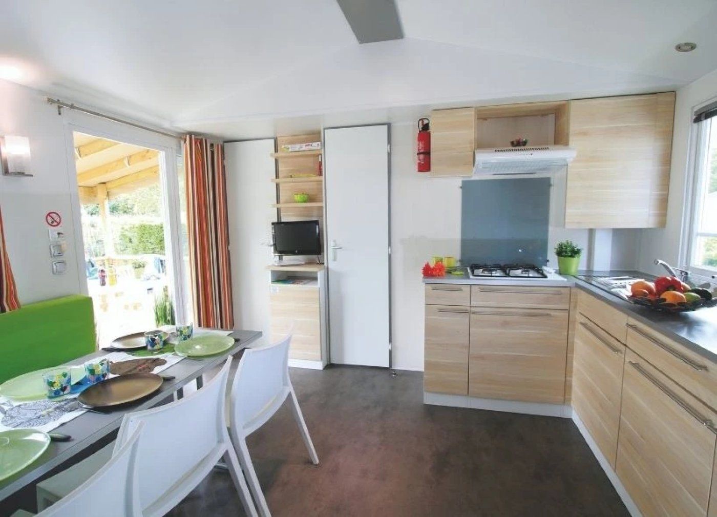 Een kleine keuken met een eethoek, een televisie en een brandblusser.
