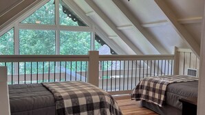 A bedroom with two beds, a ceiling fan, and large windows overlooking a deck. - Charming 2-bedroom house with AC, WiFi in the Sky Valley Country Club. (Dillard)