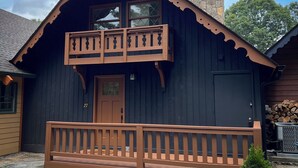 A wooden cabin with a balcony, a stone chimney, and a number 27 sign. - Charming 2-bedroom house with AC, WiFi in the Sky Valley Country Club. (Dillard)