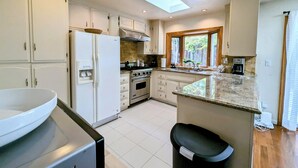 A kitchen with white cabinets, a built-in oven, a sink, and a skylight.